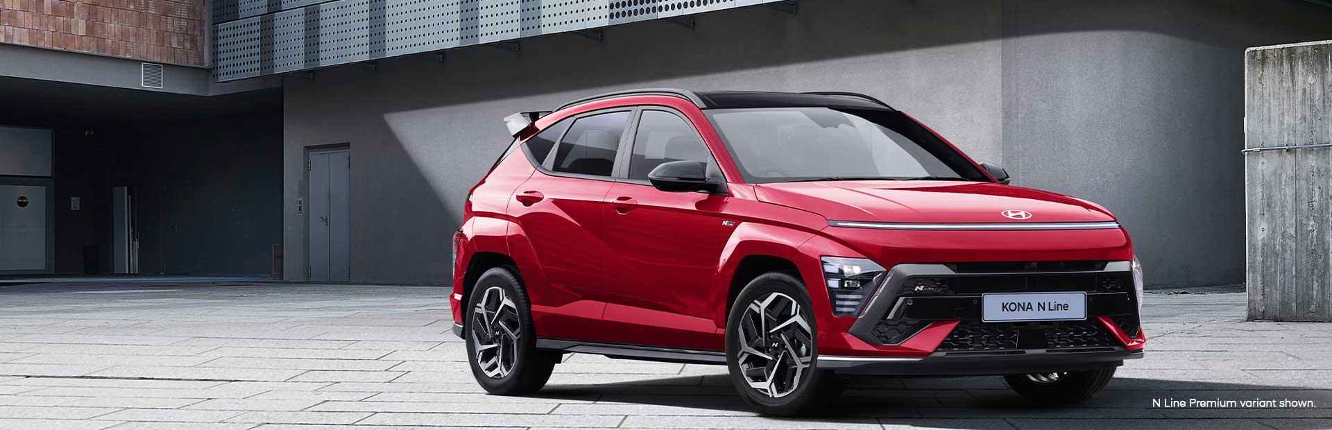 The Hyundai KONA N Line in vibrant red, parked in a modern urban setting, showcasing its bold exterior design, sporty accents, and dynamic stance.